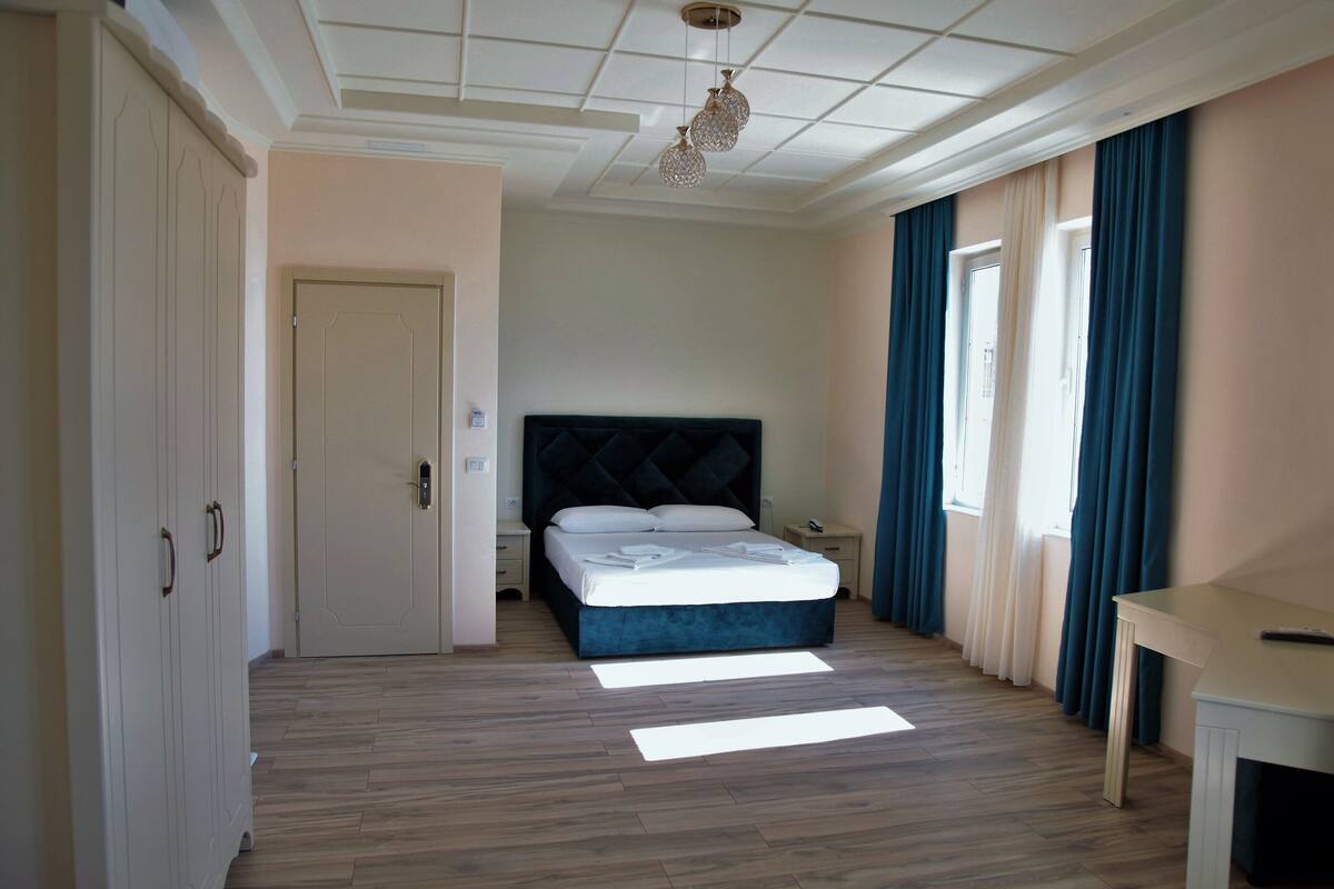 A bedroom with a bed, a nightstand, a desk, and a wardrobe.
