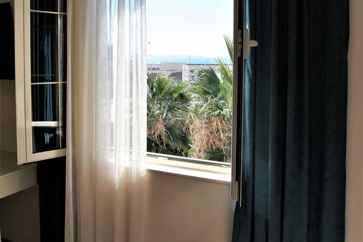 A room with a window, a sliding door, and a view of greenery outside.