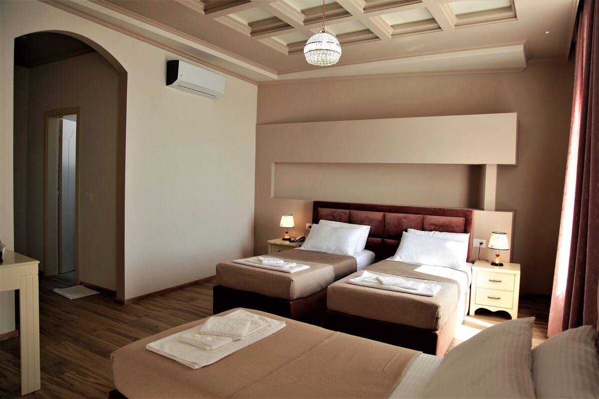 A hotel room with two beds, a desk, and a chandelier.