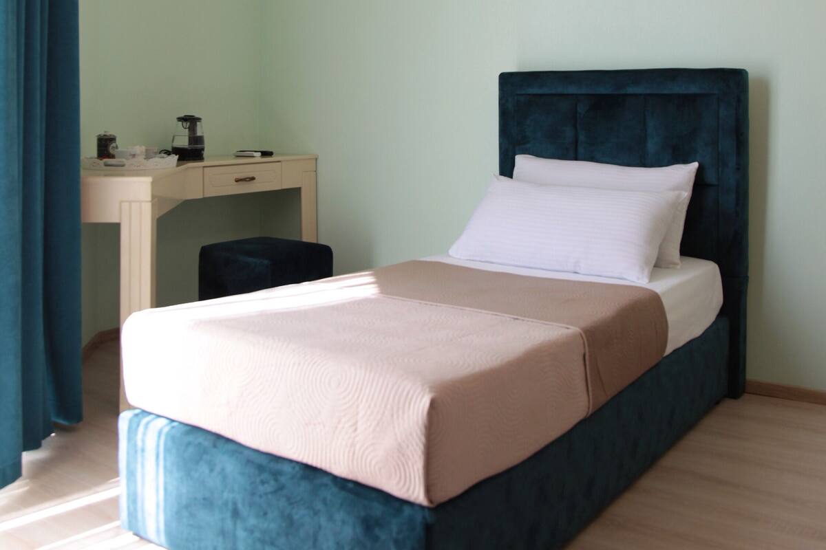 A bedroom with a bed, a desk, and an air conditioning unit.