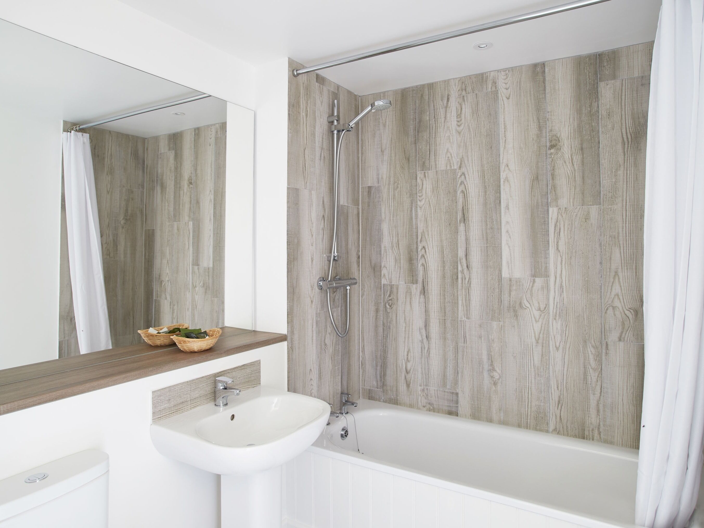 Une salle de bain moderne avec un mur en bois, un lavabo blanc et une baignoire.