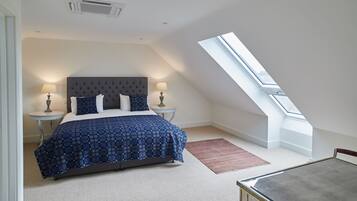 Une chambre à coucher avec un lit, deux tables de chevet, une lampe, un tapis rouge et une lucarne.