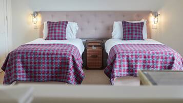 Une chambre double avec deux lits, chacun agrémenté d'une couvre-lit à motifs et d'oreillers assortis, d'une commode en bois et de luminaires fixés au mur.