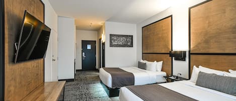 Une chambre d’hôtel avec deux lits, un bureau, un téléviseur à écran plat et un sol recouvert de moquette.