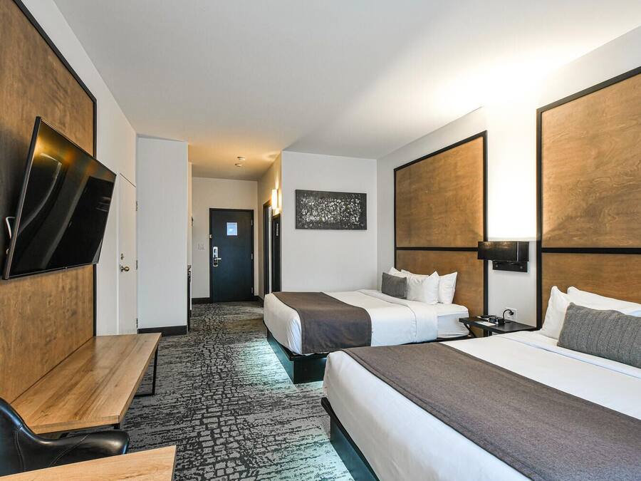 Une chambre d’hôtel avec deux lits, un bureau, un téléviseur à écran plat et un sol recouvert de moquette.