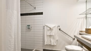 A modern bathroom with a shower area, a toilet, and a sink with a mirror.