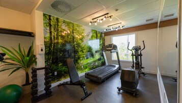 Un gimnasio con cinta de correr, elíptica y máquinas de pesas.
