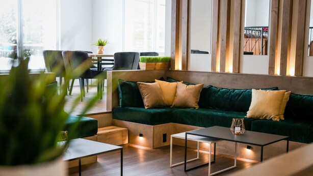 A modern living room with a green sofa, two side tables, and a coffee table.