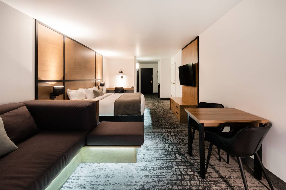 Una habitación de hotel moderna con sofá, cama, escritorio y televisor.