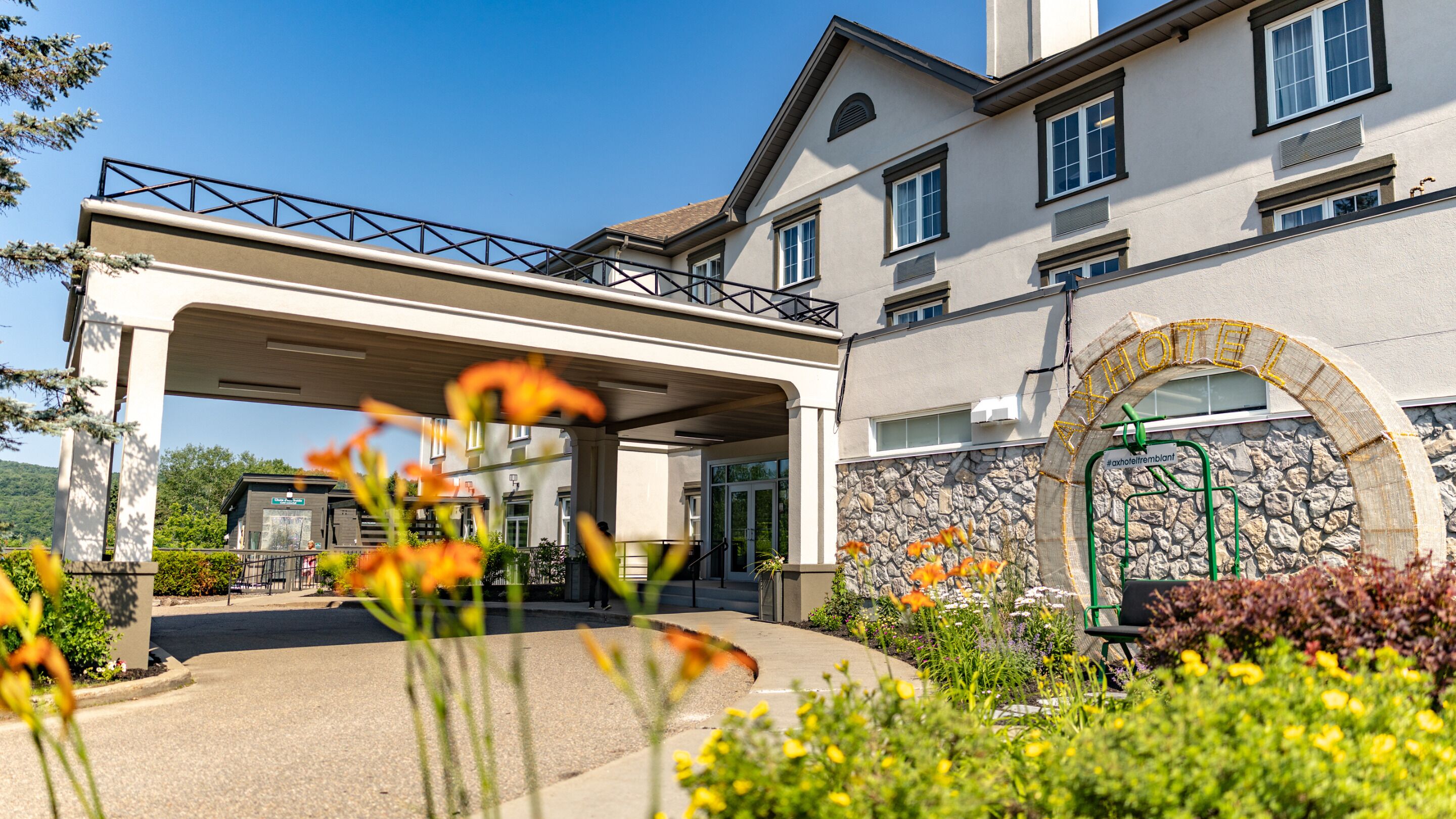 A hotel entrance with a covered walkway, stone archway, and a landscaped garden.