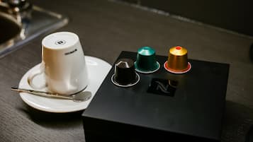 A coffee cup on a saucer with a spoon, a black box with three colored buttons, and a logo on the box.