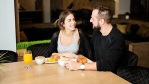 A dining table with a glass of orange juice, a bowl of soup, and a croissant.