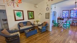 Un salon chaleureux avec un canapé, deux fauteuils, une table basse et un coin repas comprenant une table et des chaises.