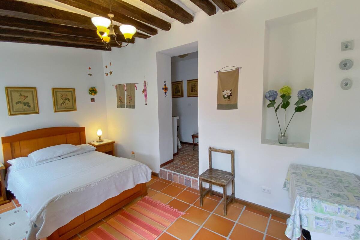 A bedroom with a wooden bed, bedside lamps, a chair, and a small table.