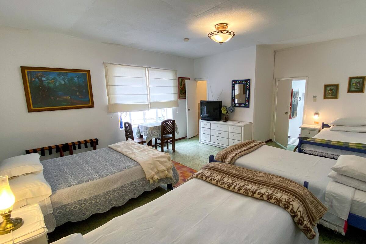 A room with two beds, a television, a desk, and a chair.