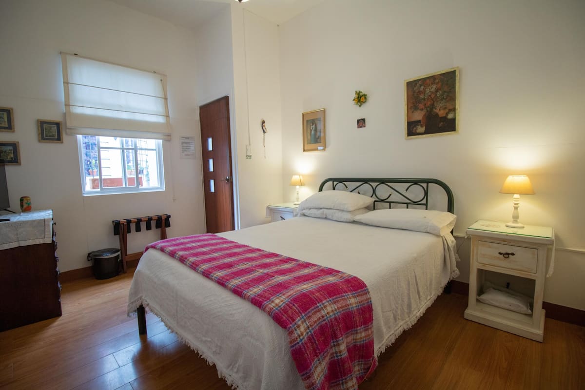 A bedroom with a bed, bedside tables, a window, and a door.