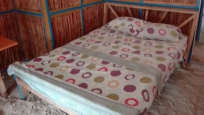 Ein Einzelbett mit einem bettenüberzug mit Punkten in einem Raum mit Wänden aus Bambuspaneelen.