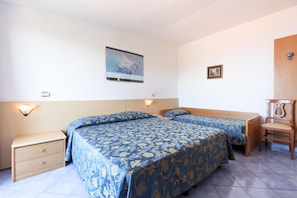 Habitación de hotel con dos camas, una mesita de noche, una silla, un cuadro en la pared y una pequeña mesa.