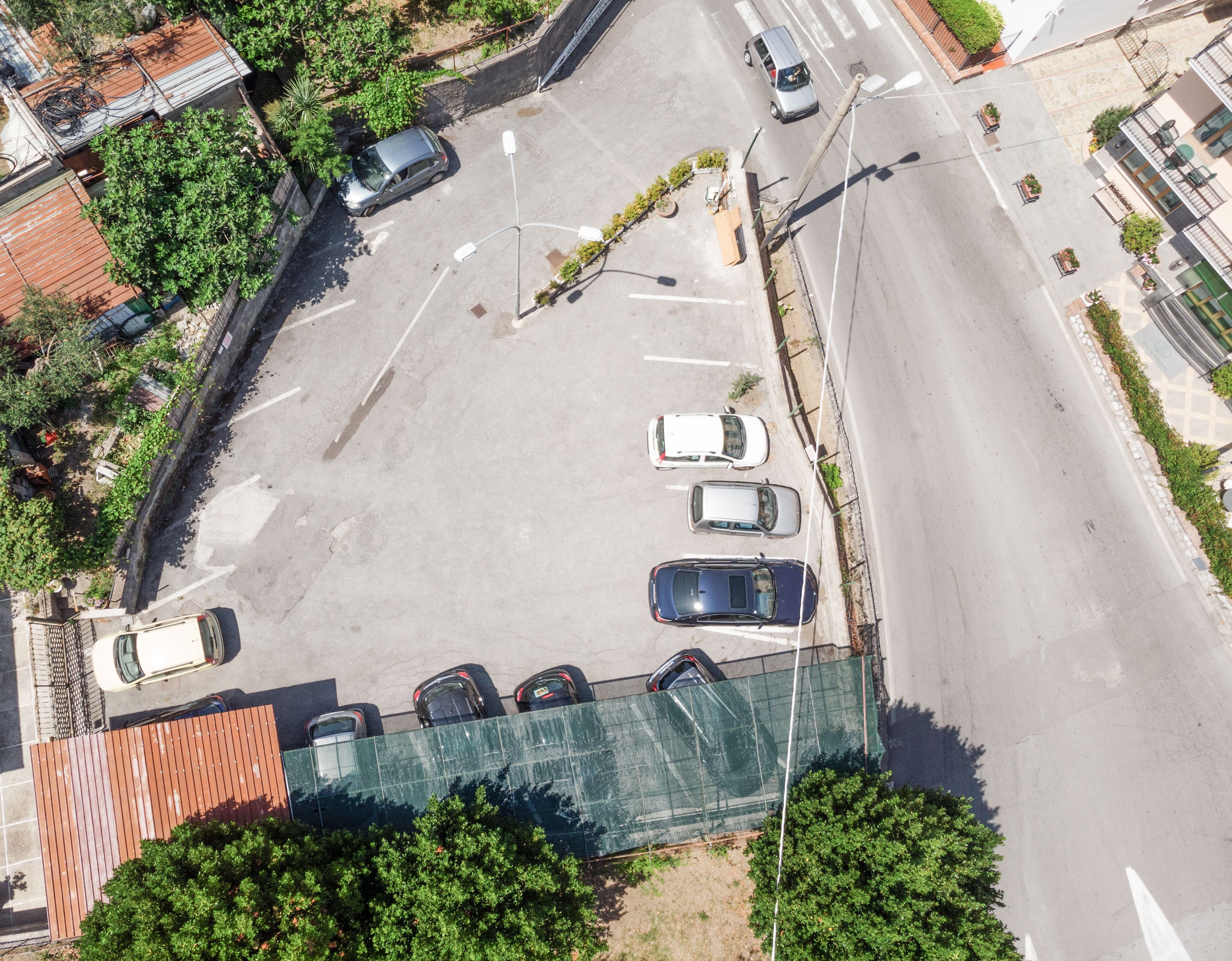 Vue aérienne d’un parking avec plusieurs voitures, d’un bâtiment doté d’un toit végétalisé et d’un espace verdoyant environnant.