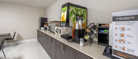 Una estación de café con una máquina de café, un refrigerador y un cartel que explica el proceso del servicio de café.