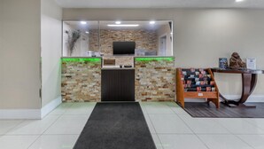 A reception area with a stone wall, a flat-screen TV, a desk, and a display of brochures. - SureStay Hotel by Best Western Kemptville (North Grenville)