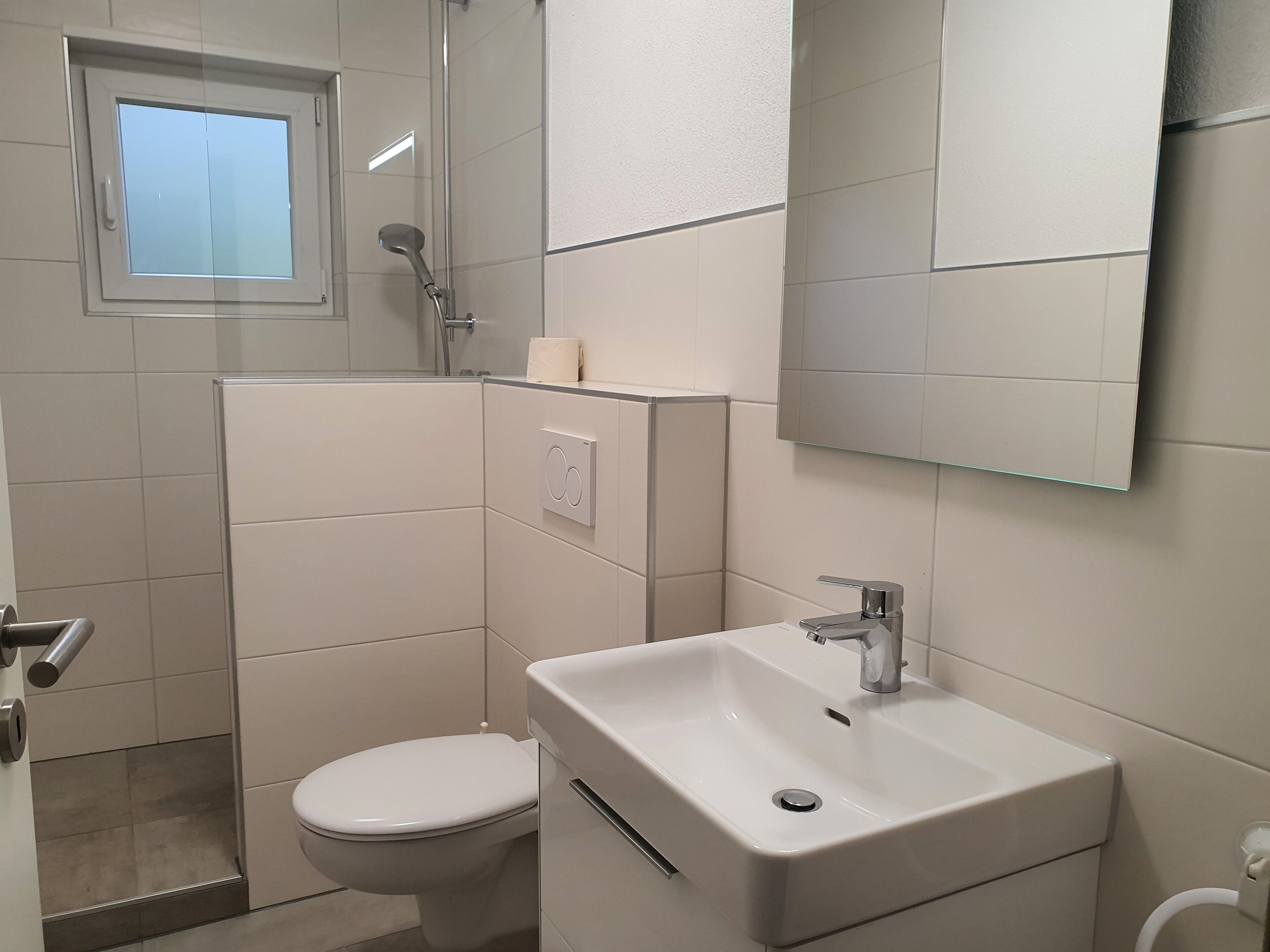 Une salle de bain moderne équipée de toilettes, d’une douche et d’un lavabo.