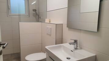 Une salle de bain moderne équipée de toilettes, d’une douche et d’un lavabo.
