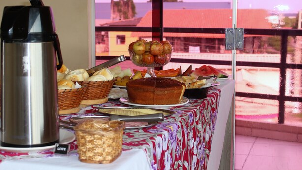 A breakfast buffet with various baked goods, a cake, and a fruit bowl. - Pratico Hotel (Santarém)
