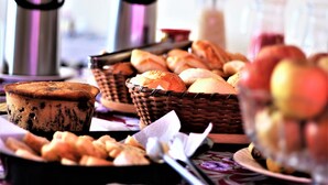 A table with various food items including pastries, a pie, and a bowl of fruit. - Pratico Hotel (Santarém)