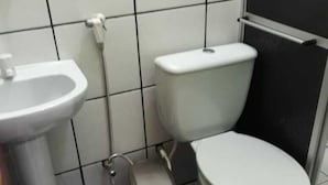 Um banheiro pequeno com uma pia branca, um vaso sanitário e uma lixeira.