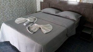 Cama bem arrumada com colcha cinza e dois travesseiros.
