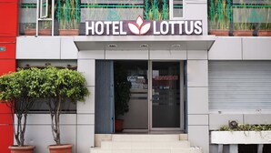 Ein Hotel Eingang mit einem Schild mit der Aufschrift 'HOTEL LOTTUS' und einem Willkommensschild.