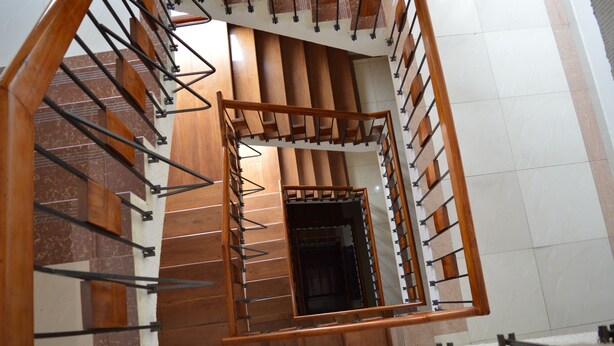 Eine Wendeltreppe mit Holzgeländern und Metallstützen, die zu einer oberen Etage führt.