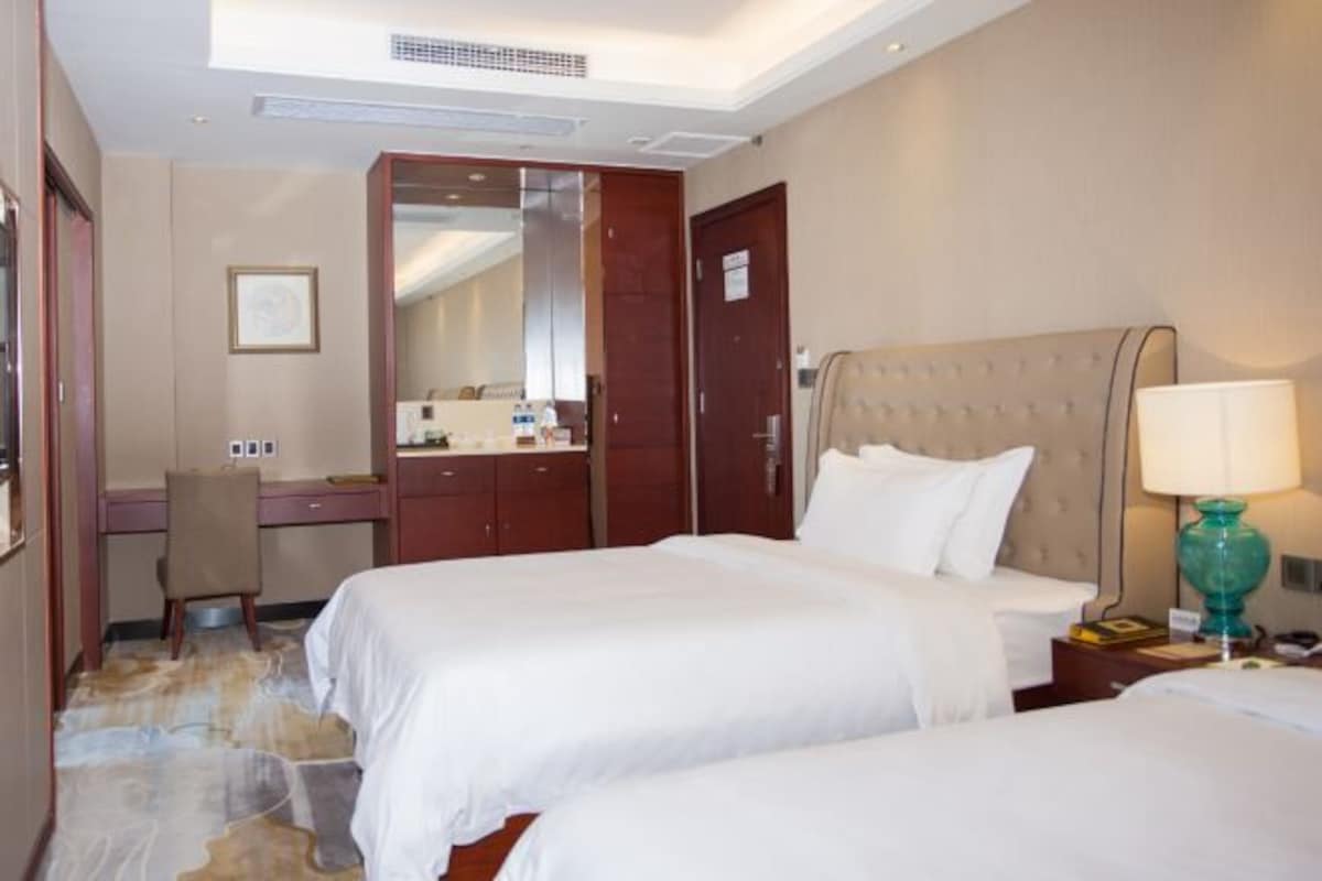 Une chambre d’hôtel avec deux lits, un bureau et une chaise.