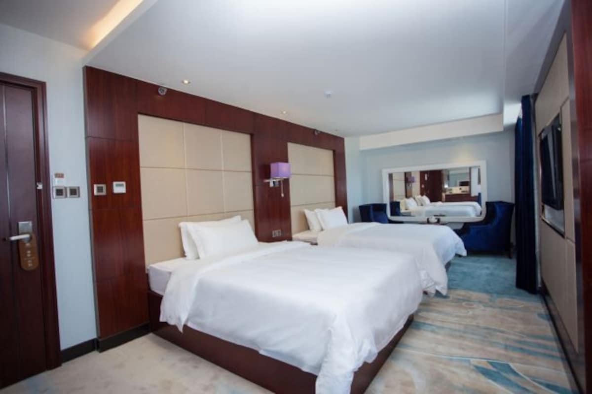 Une chambre d’hôtel avec deux lits, un grand miroir, un bureau et une salle de bain.