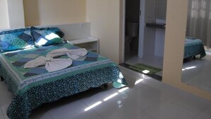 Un dormitorio con cama, mesita de noche y puerta al baño.