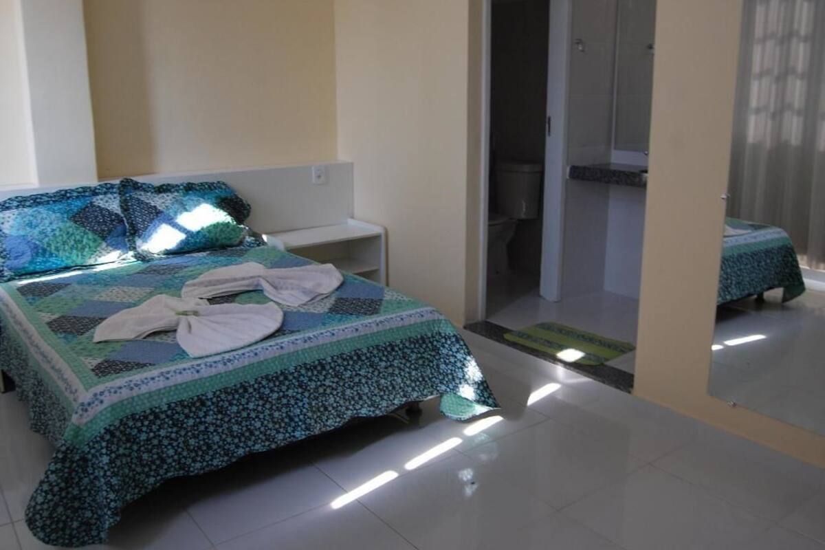 A bedroom with a bed, a nightstand, and a bathroom door.