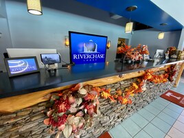 A reception desk with a Riverchase Lodge sign, a computer monitor, a tablet, and autumn-themed decorations.