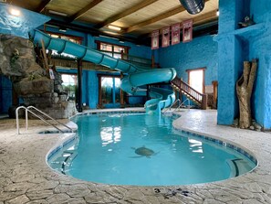 Una piscina interior con tobogán, una tortuga y una escalera de madera.