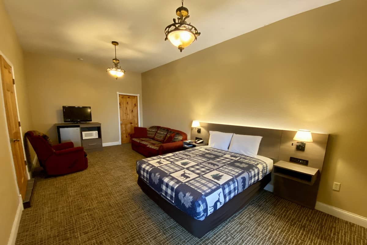Un dormitorio con una cama grande, una silla roja, un televisor y una puerta de madera.