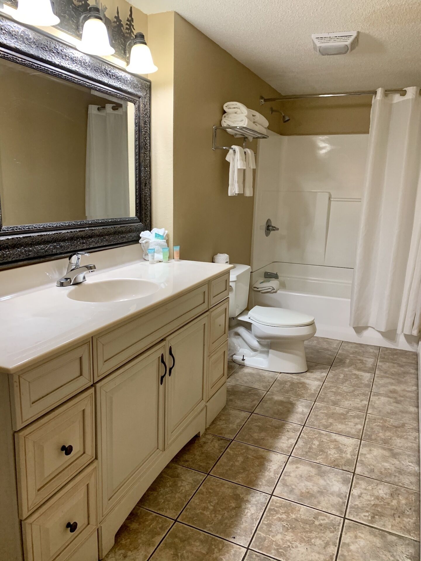 A bathroom with a sink, mirror, toilet, and bathtub.