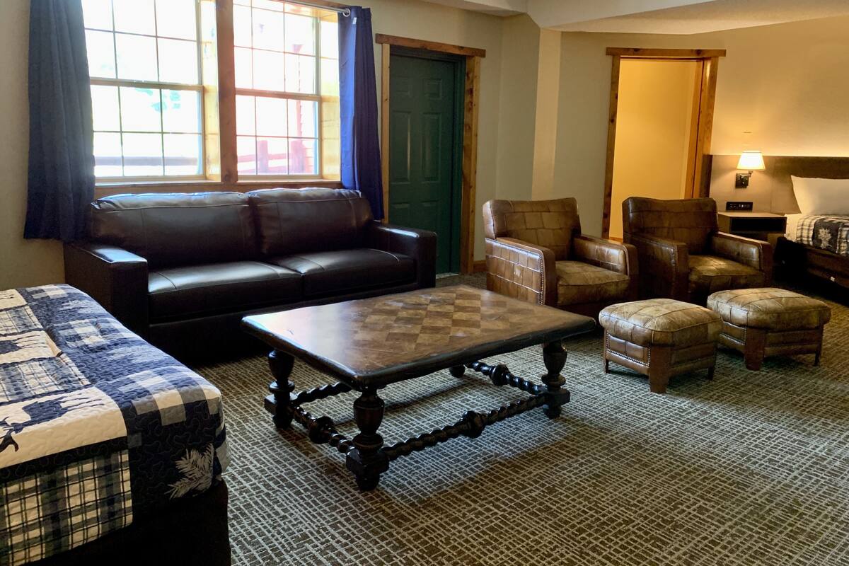 Un salón acogedor con un sofá de cuero, una mesa de centro de madera y una puerta verde.