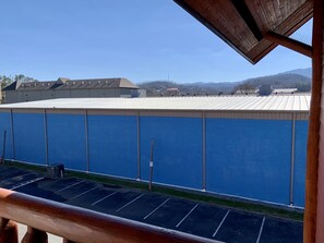 A view of a building with a blue exterior wall and a metal roof, with mountains in the background.