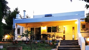 A modern house with a covered patio, outdoor seating, and a garden with potted plants. - Villa Irene (Kos)