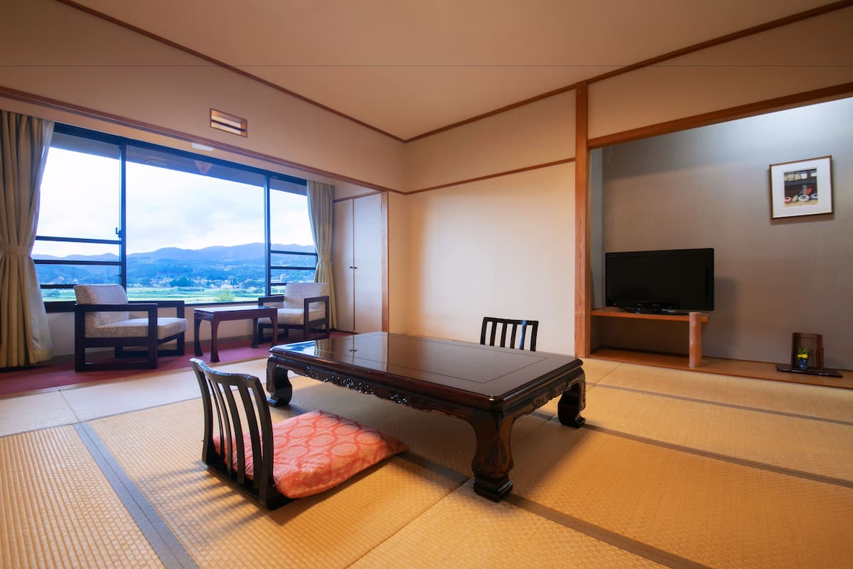 A traditional Japanese room with tatami flooring, a low table, and chairs.