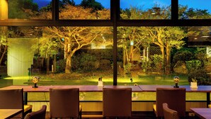 A dining area with a view of a garden at night. - Yufuin Sansuikan (Yufu)