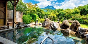 A traditional Japanese onsen with a wooden bathhouse, clear hot spring water, and a mountain in the background. - Yufuin Sansuikan (Yufu)