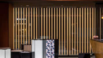 A modern interior with vertical wooden slats, a patterned column, and sleek black furniture.