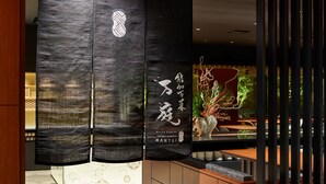 A modern interior with a dark textured wall, a glass display case, and a wooden counter. - Mitsui Garden Hotel Kanazawa (Kanazawa)