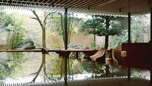 An indoor space with a water feature, wooden slats, and a seating area with cushions. - Mitsui Garden Hotel Kanazawa (Kanazawa)